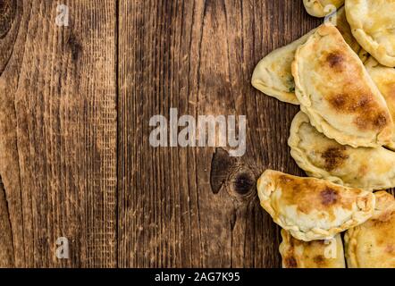 Holztisch mit frischen, hausgemachten Empanadas (detaillierte Nahaufnahme; selektive Fokus) Stockfoto