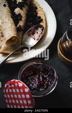 Hochwinkel vertikale Schuss von leckeren Crepes mit Heidelbeermarmelade Auf einer schwarzen Oberfläche Stockfoto