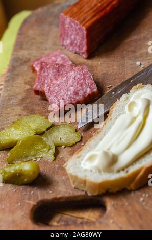 Geräucherte Wurst, Gurken und Brot. Traditionelle ukrainische Küche. In Scheiben geschnitten Produkte auf einer hölzernen Schneidebrett. Selektive konzentrieren. Stockfoto