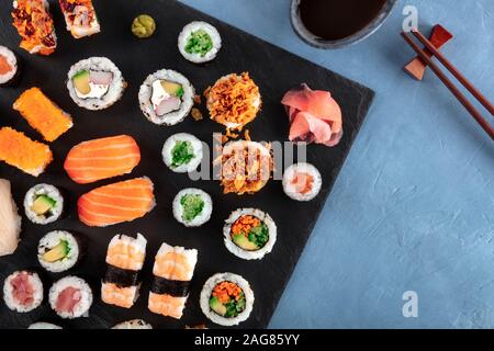 Große sushi Set, Schuß von oben auf einen Schiefer Hintergrund mit Stäbchen und Sojasauce. Eine Zusammenstellung der verschiedenen Maki, Nigiri und Rollen Stockfoto