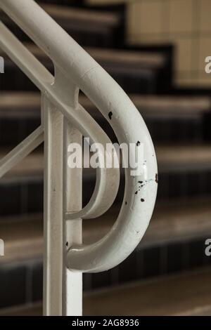 Vertikale Nahaufnahme eines weißen Geländers und des verschwommenen Treppe im Hintergrund Stockfoto