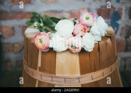 Nahaufnahme von schönen weißen und rosa Pfingstrosen auf einem Brauner Eimer aus Holz Stockfoto