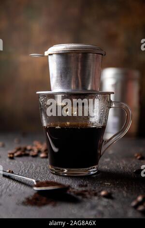 Vorbereitung der vietnamesischen Kaffee mit Aluminium cofe Filer auf dunklem Hintergrund Stockfoto