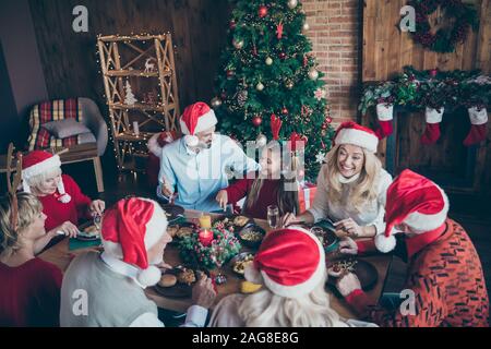 Top hohen Winkel Foto von großen Familie tragen Weihnachtsmann Mütze cap Sitzung am x-mas Eve sitzen Tisch essen sprechen unter Generation mit kleinen kleinen Jungen sprechen Stockfoto