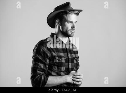 American Cowboy. Westliche leben. Mann unrasiert Cowboy beigen Hintergrund. Unrasierten Kerl in Cowboyhut. Schöne bärtige Macho. Schönheit Standard. Beispiel wahrer Männlichkeit. Cowboy Hut tragen. Stockfoto