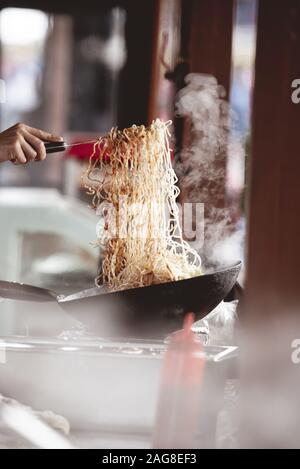 Vertikale Nahaufnahme eines Kochs, der Nudeln mit einem macht Unscharfer Hintergrund Stockfoto