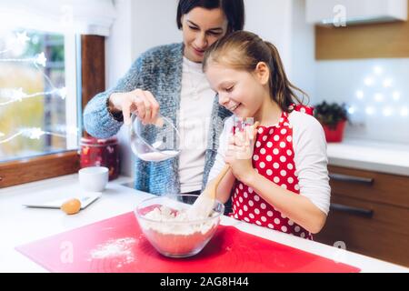Weihnachtsbäckerei. Mutter und Tochter, Lebkuchen, Zubereitung Eier, Mehl, Honig, Lebkuchen Teig. Festliche Essen, Kochen, Familie cu Stockfoto