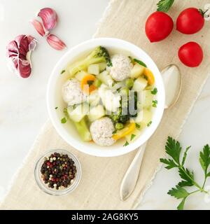 Schüssel mit Suppe, eine Tasse Brühe und Gemüse, Frikadellen aus der Türkei und ein Huhn, Ansicht von oben Stockfoto