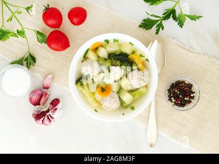 Schüssel mit Suppe, eine Tasse Brühe und Gemüse, Frikadellen aus der Türkei und ein Huhn, Ansicht von oben Stockfoto