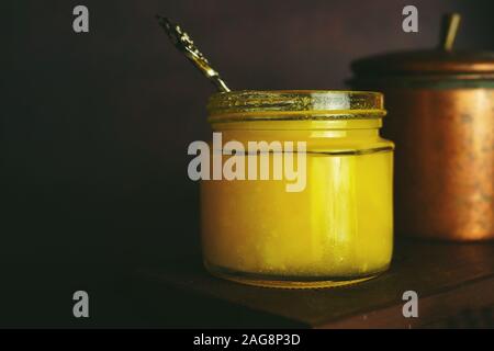 Hausgemachte Ghee/Butterschmalz in einem Glas auf dunklen Moody Hintergrund, selektiver Fokus Stockfoto