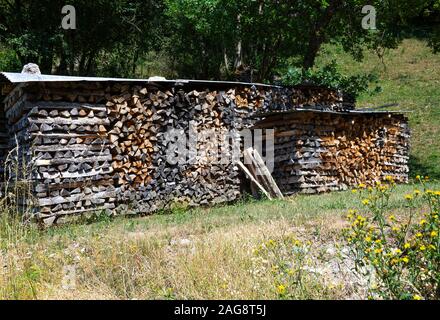 In einem Garten Montriond Portes du Soleil France Wurden In Den Wintermonaten bedeckte Holzhaufen Für Brennholz und brennendes Brennholz verwendet, um Wärme Zu Geben Stockfoto