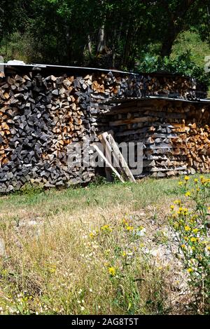 In einem Garten Montriond Portes du Soleil France Wurden In Den Wintermonaten bedeckte Holzhaufen Für Brennholz und brennendes Brennholz verwendet, um Wärme Zu Geben Stockfoto