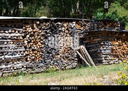 In einem Garten Montriond Portes du Soleil France Wurden In Den Wintermonaten bedeckte Holzhaufen Für Brennholz und brennendes Brennholz verwendet, um Wärme Zu Geben Stockfoto