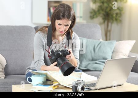 Verwirrt touristische versuchen, ein komplizierter DSLR-Kamera auf einer Couch im Wohnzimmer zu Hause sitzen zu setzen Stockfoto