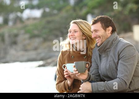Glückliches Paar von Erwachsenen dating Kaffee trinken, die Aussicht im Winter am Strand Stockfoto