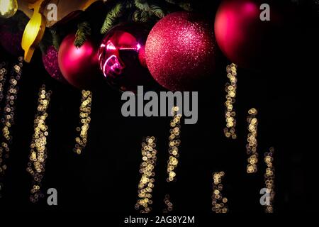 Red christmas Ornamente und Bokeh festliche Lichter im Hintergrund, in Weimar Weihnachtsmarkt gesehen, Deutschland. Stockfoto