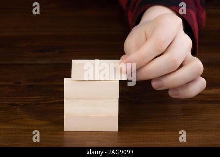 Hand Holzwürfel mit Flip über Block am Tisch Hintergrund Stockfoto