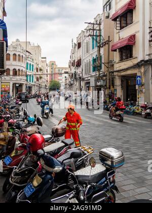 HAIKOU, HAINAN, CHINA - Mar 2 2019 - Motorräder, Motorroller und Fahrräder entlang der Bürgersteige an Bo'geparkt ai Straße, während Autofahrer und Pendler Stockfoto