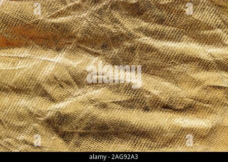 Textur von Golden zerknittert Stoff Tuch. Zusammenfassung Hintergrund für Gestaltung mit kopieren. Stockfoto