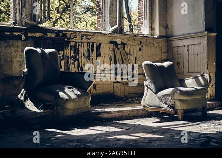 Verlassene Haus mit zwei abgenutzten Sofas und kaputten Fenstern während Tagsüber Stockfoto