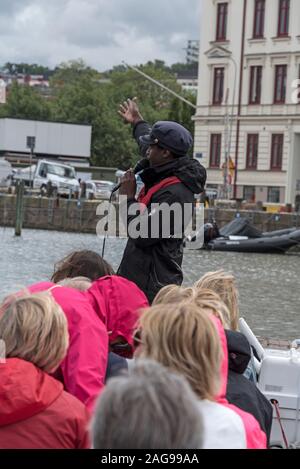 Ein Boot Führung an der Vorderseite des touristischen Boot, die mesopotamien Sightseeing Tour, die eine Gruppe von Touristen auf einem der Kanäle in Göteborg, Schweden. Stockfoto