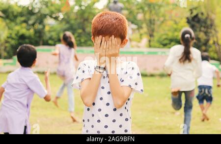 Kinder spielen Verstecken und im Park suchen - multi-ethnische Kinder spielen Spiele im Freien Stockfoto