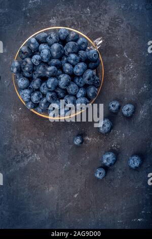 Frische Heidelbeeren in eine Glasschüssel auf dunklem Hintergrund, Ansicht von oben Stockfoto