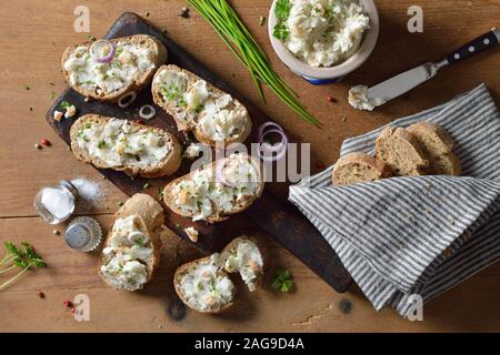 Herzhaftes Schmalz mit Grieben und Zwiebeln als Aufstrich auf frisches Vollkornbrot Baguette, serviert auf einem rustikalen Holztisch Stockfoto