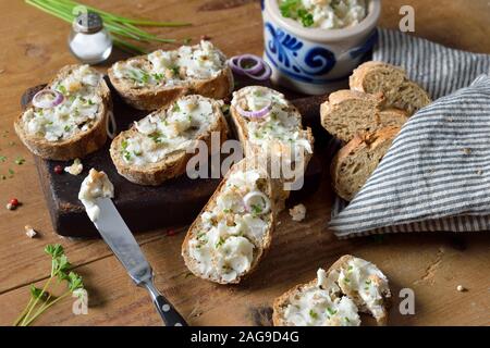 Herzhaftes Schmalz mit Grieben und Zwiebeln als Aufstrich auf frisches Vollkornbrot Baguette, serviert auf einem rustikalen Holztisch Stockfoto