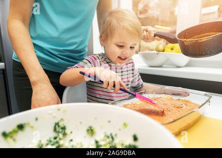 Mutter und Tochter kochen vegetarische Lasagne gemeinsam in der Küche zu Hause Stockfoto