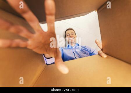 Lächelnder Mann, der in der Verpackung und das Erreichen für Waren Stockfoto