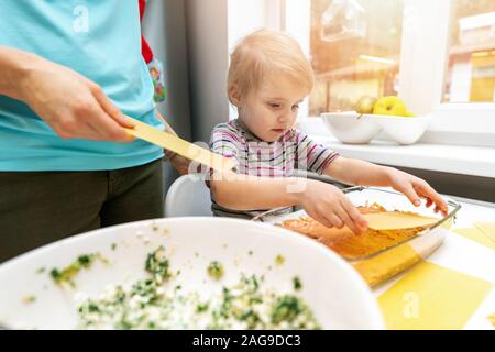 Mutter und Tochter zusammen kochen in der Küche zu Hause. putting Lasagne Blätter Stockfoto