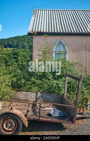 Ein altes Gebäude aus Wellblech, das ein Bogenfenster und einen alten verschlissenen Anhänger außerhalb von Talybont-on-Usk, Wales hat Stockfoto