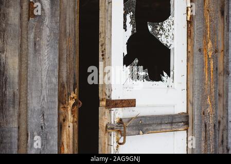 Ein zerbrochenes Fenster in der Tür, mit scharfen, gefährliche Kanten von Splitter- und abblätternde Farbe. Stockfoto