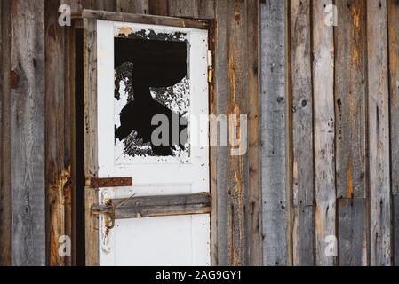 Ein zerbrochenes Fenster in der Tür, mit scharfen, gefährliche Kanten von Splitter- und abblätternde Farbe. Stockfoto