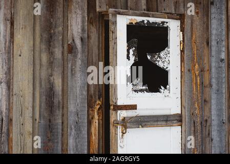 Ein zerbrochenes Fenster in der Tür, mit scharfen, gefährliche Kanten von Splitter- und abblätternde Farbe. Stockfoto