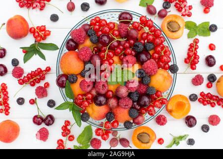 Frische und süße Sommer Beeren in der Platte auf weißem Hintergrund. Himbeere, Brombeere, Johannisbeere, Johannisbeere, Stachelbeere, Aprikose, Kirsche und Minze. Top vi. Stockfoto