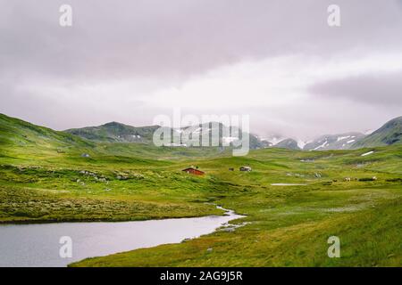 Norwegische Holz- Sommer Haus mit Blick auf den malerischen See, Norwegen, Skandinavien. Ferienhaus am See in Ländlichen. Torf überdachte Hütte am See. Typische Gras überdacht Stockfoto