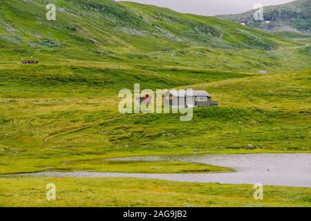 Norwegische Holz- Sommer Haus mit Blick auf den malerischen See, Norwegen, Skandinavien. Ferienhaus am See in Ländlichen. Torf überdachte Hütte am See. Typische Gras überdacht Stockfoto