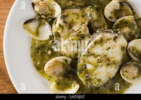 Seehecht Fischen und Muscheln mit grüner Soße auf hölzernen Tisch. Typische spanische Rezept. Stockfoto