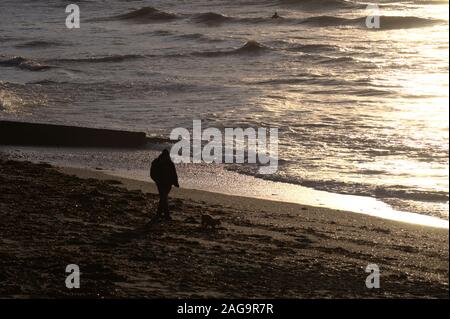 Mann in der Silhouette zu Fuß seinen Hund am Wasser Stockfoto