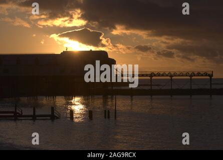 Denkmalgeschützte Wales die älteste Pier 1864 erbaut von eugenius Birke, in Silhouette mit der Einstellung Himmel und der Engel des Krieges gezeigt. Stockfoto