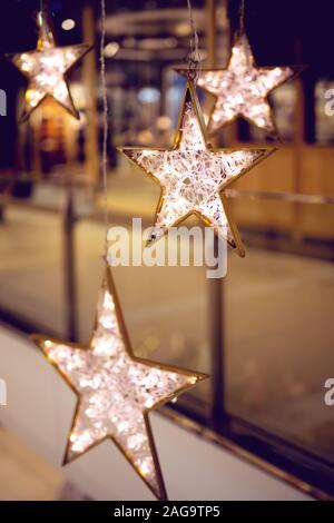 Dekorative Sterne mit Beleuchtung. Weihnachten Hintergrund mit Sternen und Garland in einer City Shopping Mall Stockfoto