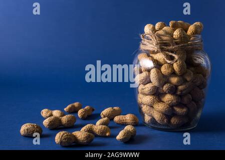 Ein Haufen von gerösteten Erdnüssen auf eine trendige blauer Hintergrund mit Platz für Design und Ihren Text. Konzept. Landwirtschaft Stockfoto