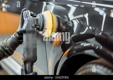 Auto service Arbeitnehmer polieren Karosserie mit speziellen Wachs vor Kratzern, close-up. Professionelle Autoteilen und Wartungskonzept Stockfoto
