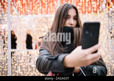 Brünette Frau mit Pullover, selfie. Frau gekleidet mit Polo Pullover unter selfie mit out of focus Handy stehen heraus, wi Stockfoto