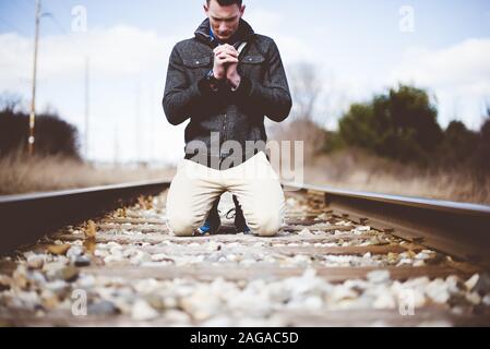 Shallow-Focus-Aufnahme eines Mannes auf den Knien Trainiere die Spuren während des Gebets Stockfoto