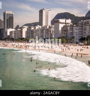 Praia do Leme, Rio de Janeiro, Brasilien, mit Touristen Füllen der Strand von Hotels und Apartments Blöcke auf dem Meer gesichert. Stockfoto