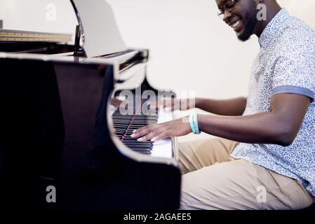 Shallow-Fokus-Aufnahme eines Mannes, der beim Spielen lächelt Klavier Stockfoto