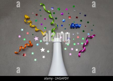 Champagner Flasche auf grauen Fliesen mit bunten Sternen und Farbband. Stockfoto